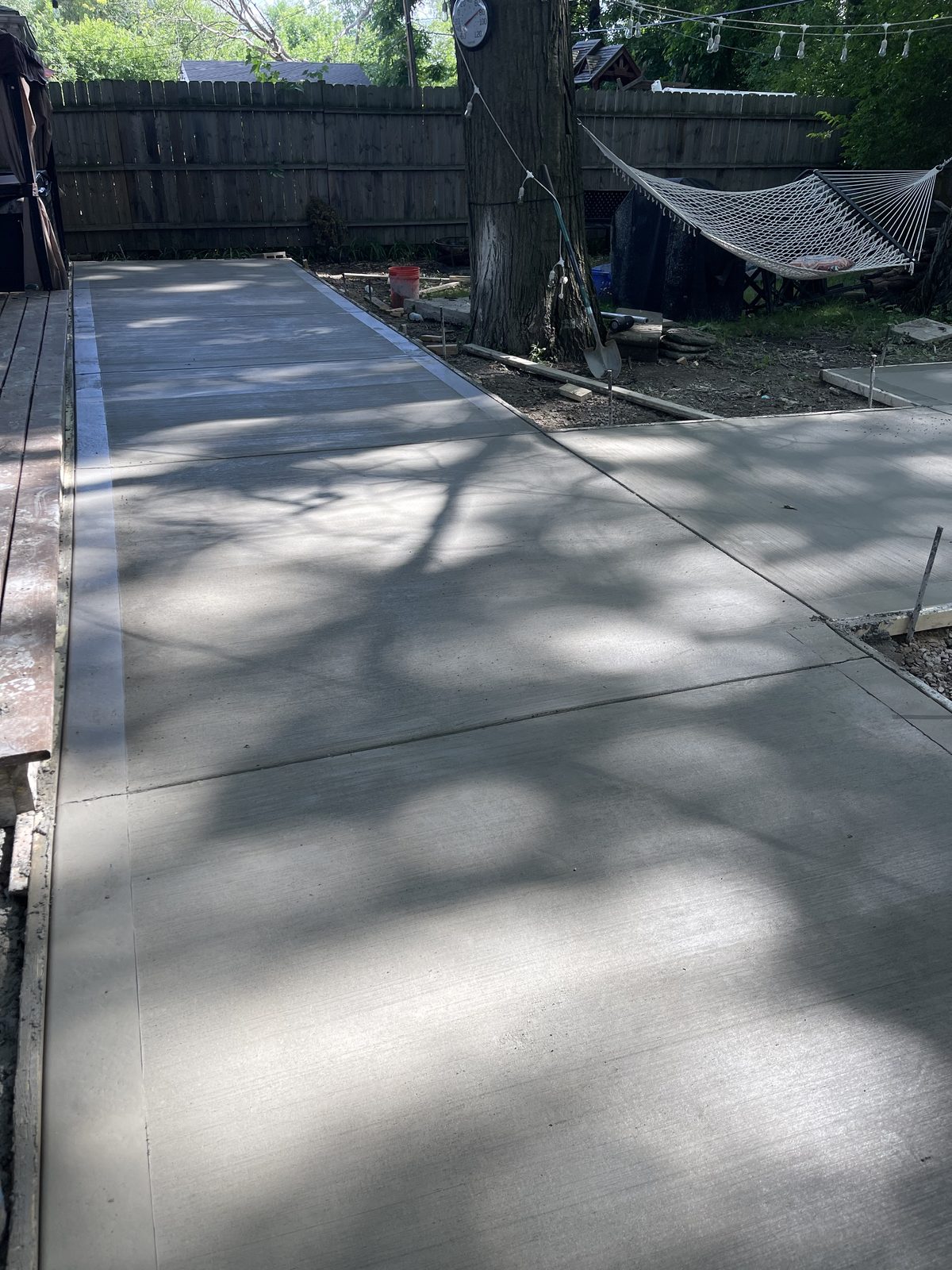 Newly poured backyard concrete pad in a shaded West Michigan yard