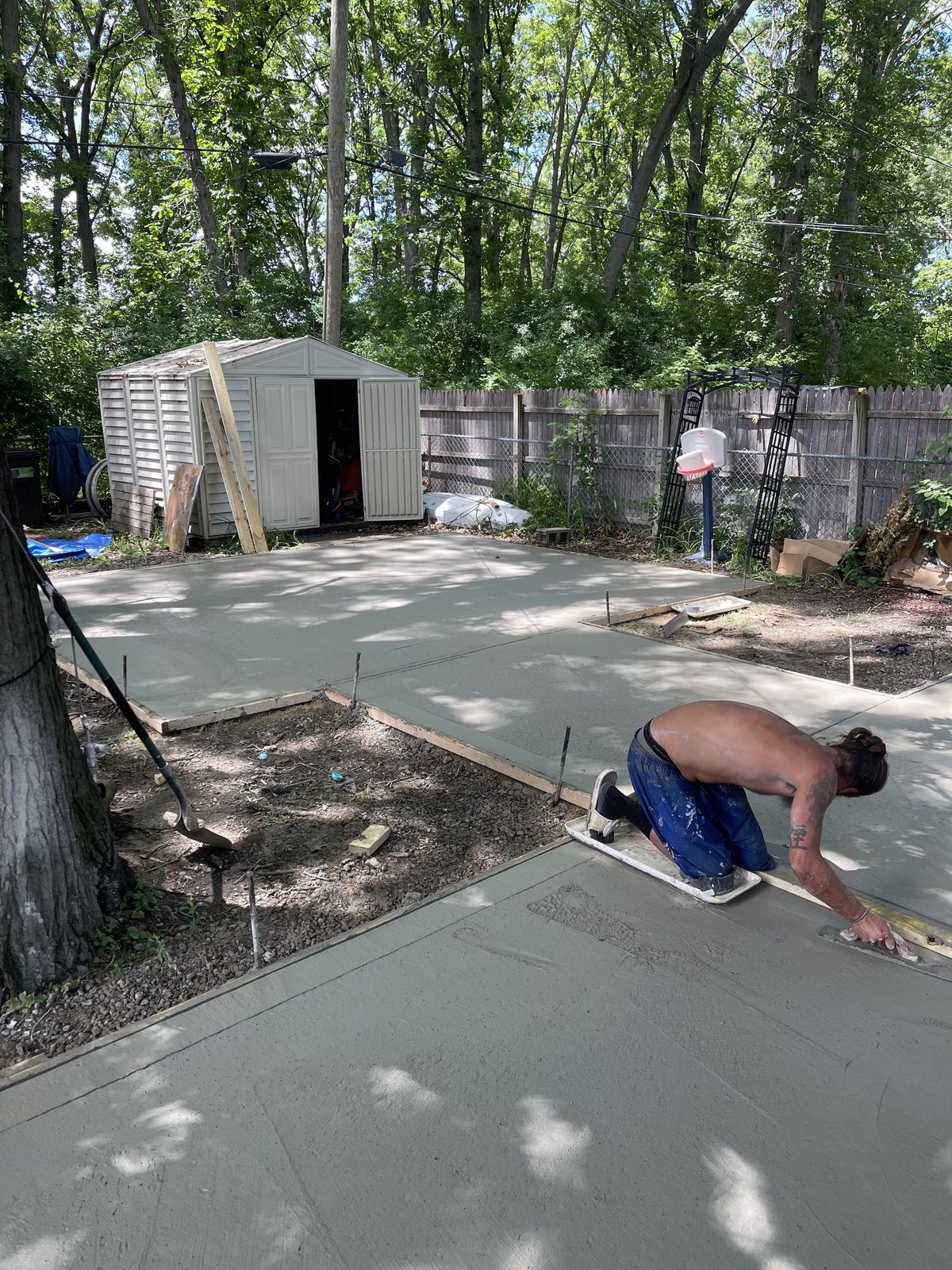 Concrete contractor hand-finishing a freshly poured backyard slab in West Michigan